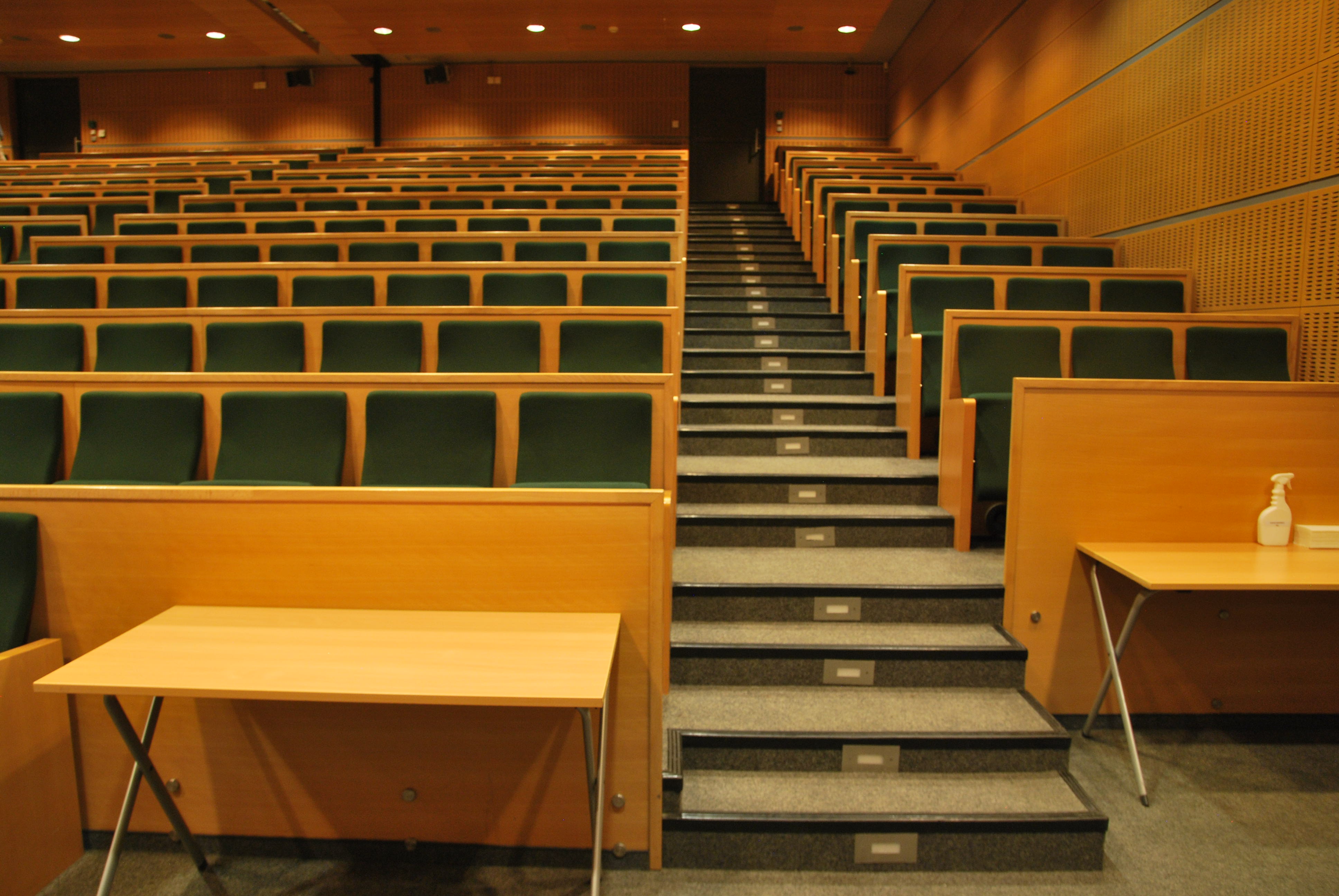 Medium Hall - a room with an amphitheatre layout. To the right is a row of triple seats with a drop-down lectern, and to the left are further rows of seats where the lectern can also be lowered. In the first row, there are movable tables and a space where a wheelchair can be placed.